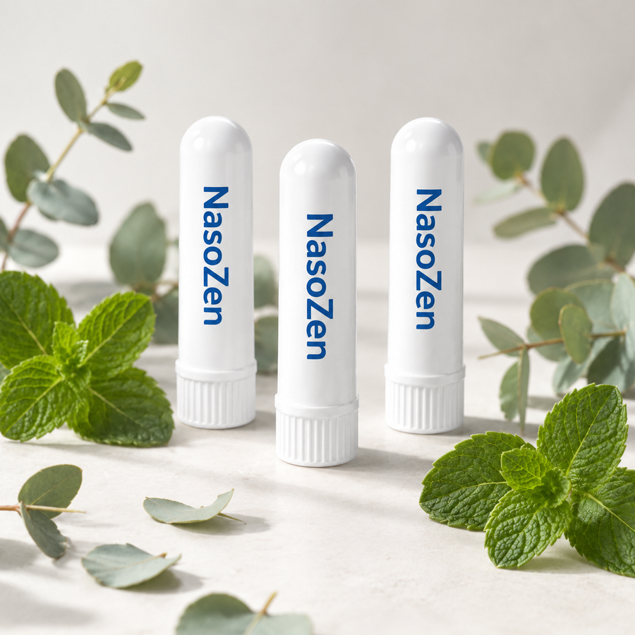 Bildprompt: Fotorealistischer Premium-Packshot — drei NasoZen Inhaler-Sticks (beigefügtes Produktbild unverändert verwenden) als Set leicht versetzt arrangiert auf hellem, cleanem Studiohintergrund, dekoriert mit frischen Pfefferminzblättern und Eukalyptuszweigen. Weiches Studiolicht, dezente Schatten, Apotheken-Premium-Look, hochauflösend.